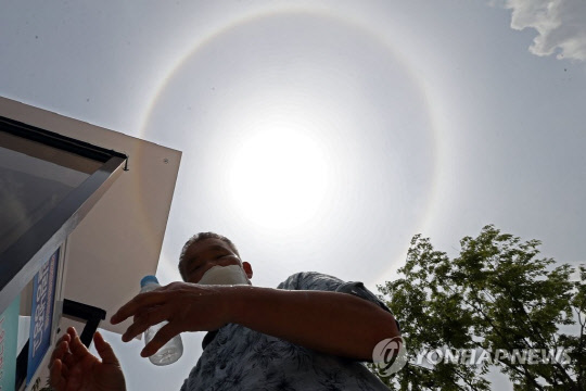 지난 20일 폭염에 대기 중 수증기로 인해 햇볕이 굴절돼 태양 주변에 둥근 모양의 무지개가 나타나는 현상인 햇무리가 생겨났다. 연합뉴스